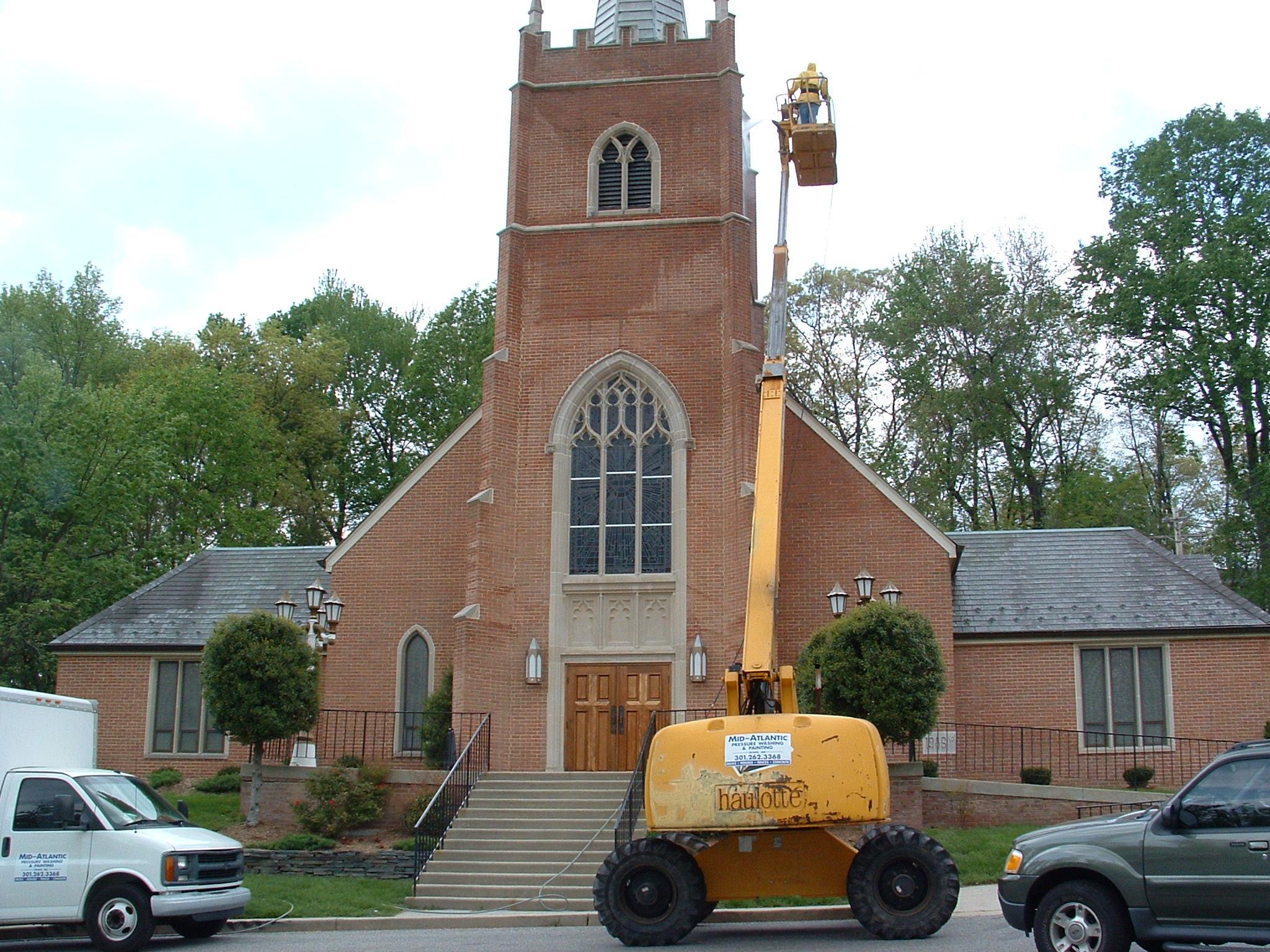 Church undergoing exterior cleaning and restoration with a lift.