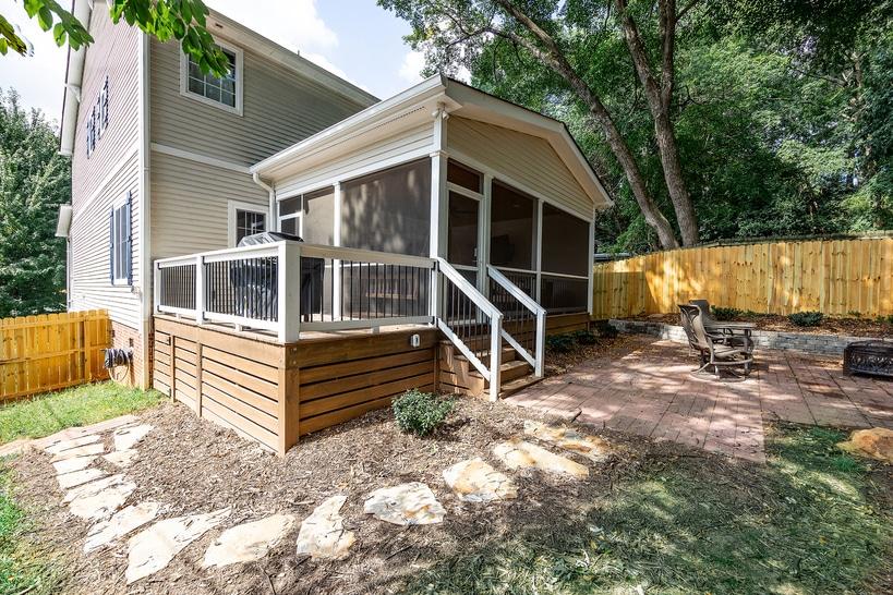 Screened-in porch home addition with elevated deck and upgraded exterior in a residential backyard.