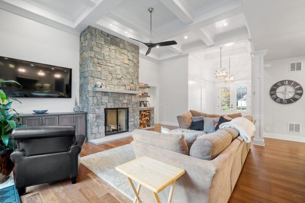 Bright living room featuring a stone fireplace and updated interior finishes.